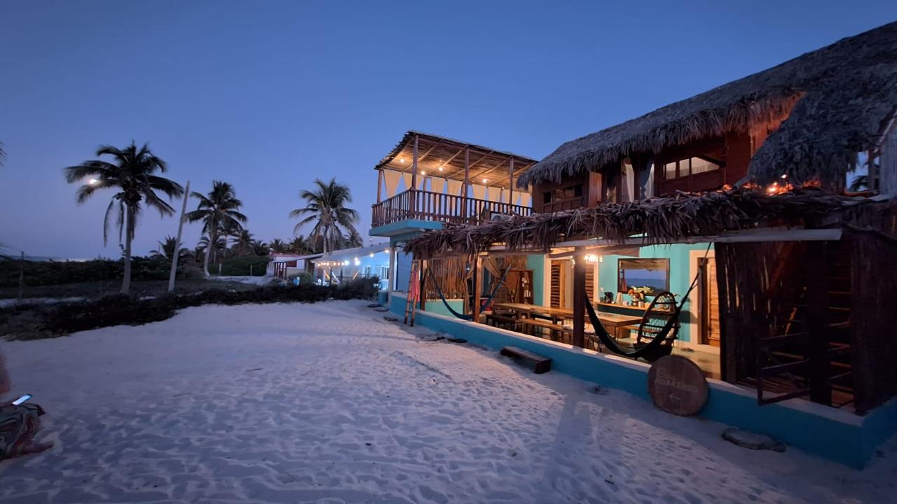 Awakening Beach House at dusk with palapa roof, hammocks and string lights on the beach of El Cuyo