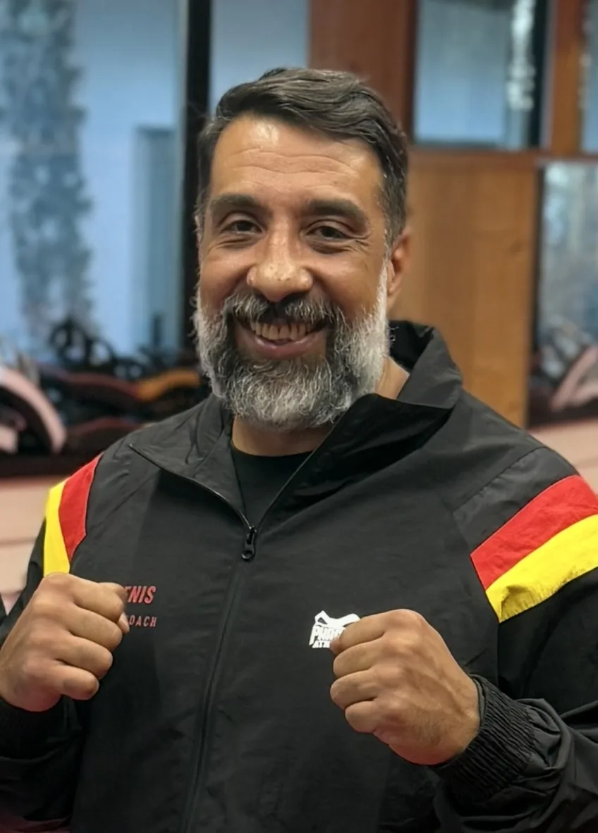 Head Coach Denis lächelt mit erhobenen Fäusten im TRIBE Gym Starnberg