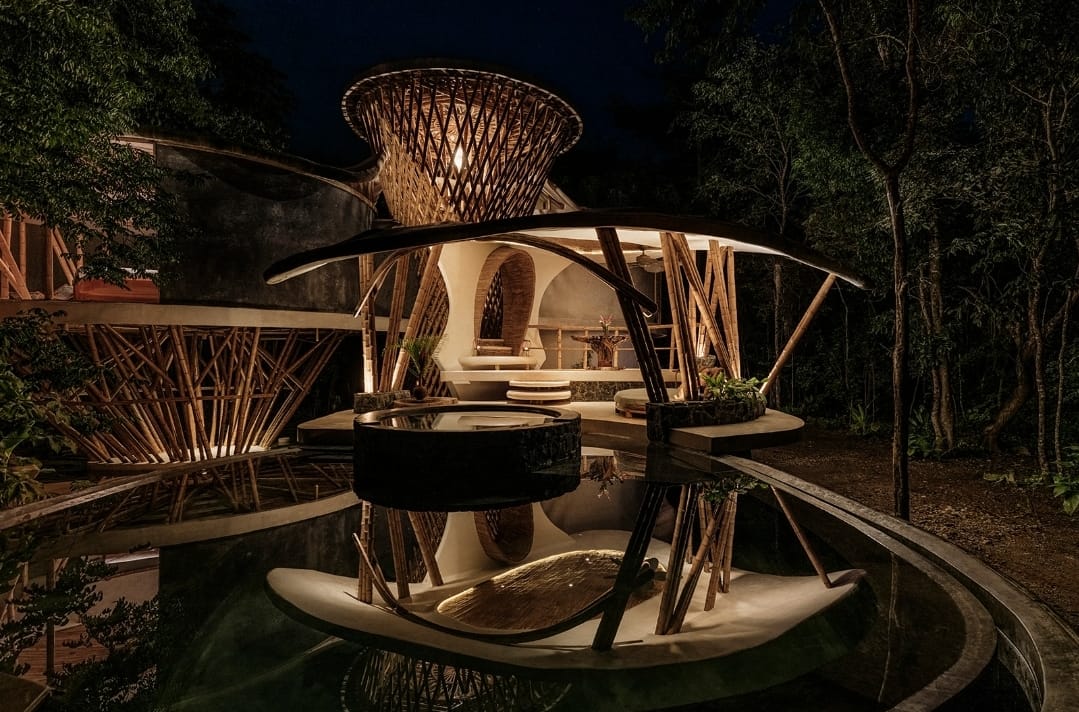 Bamboo pavilion of the Awakening Sanctuary at night reflected in the water