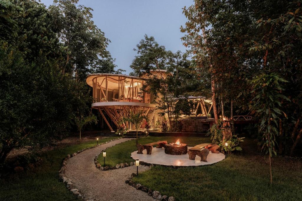 Trillium Baumhaus im Yucatán-Dschungel bei Dämmerung mit Lagerfeuer — Awakening Sanctuary San Manuel, Mexiko