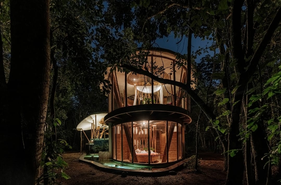 Illuminated treehouse of the Awakening Sanctuary at night in the Yucatán jungle